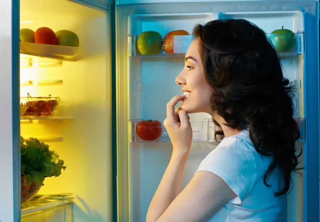 meisje kijkt in de koelkast tijdens snel gewichtsverlies